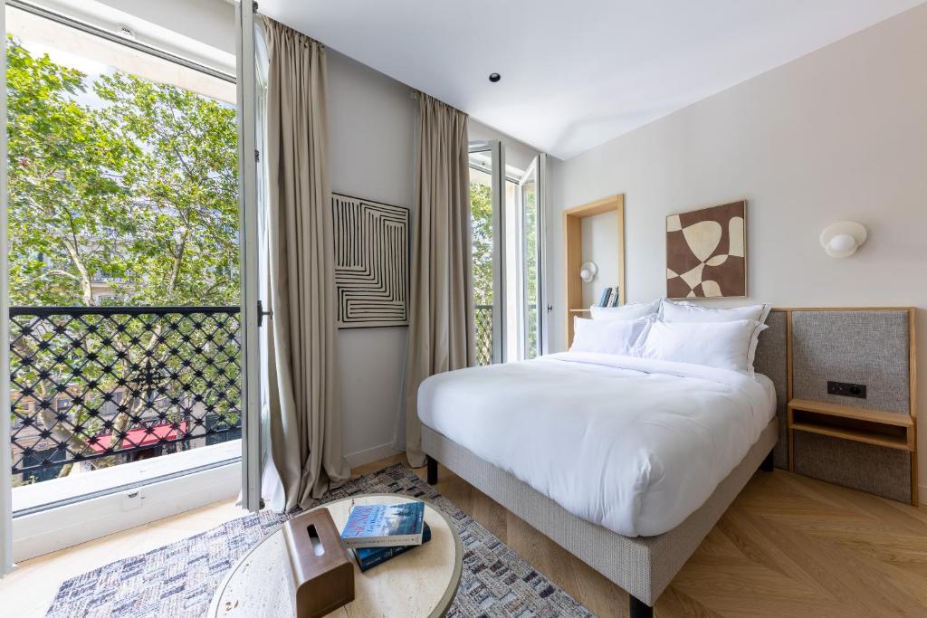a bedroom with a bed and a large window at Quartier Libre Marais in Paris
