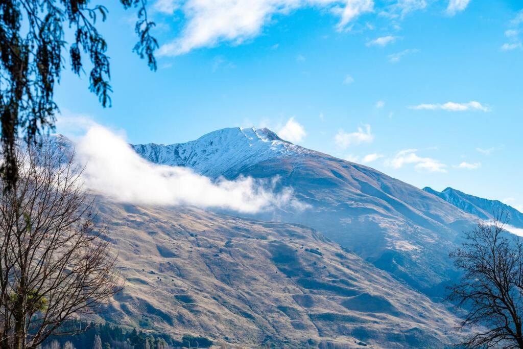 a mountain covered in snow and clouds in the sky at Stonehaven in Wanaka