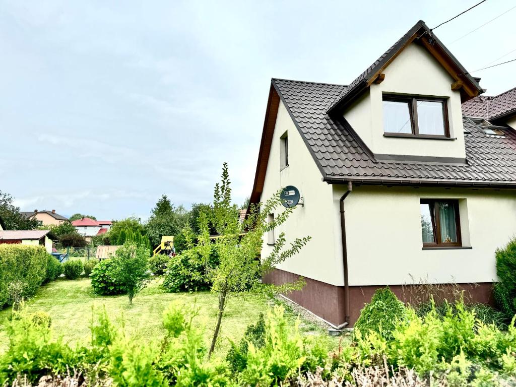 ein weißes Haus mit einem schwarzen Dach in der Unterkunft Domek u podnóża Skrzycznego in Lipowa
