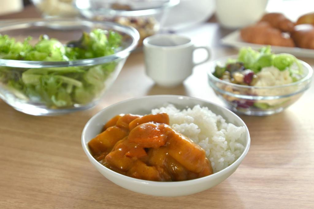 a table with a bowl of rice and a bowl of vegetables at Washington R&B Hotel Nagoya Shinkansenguchi in Nagoya