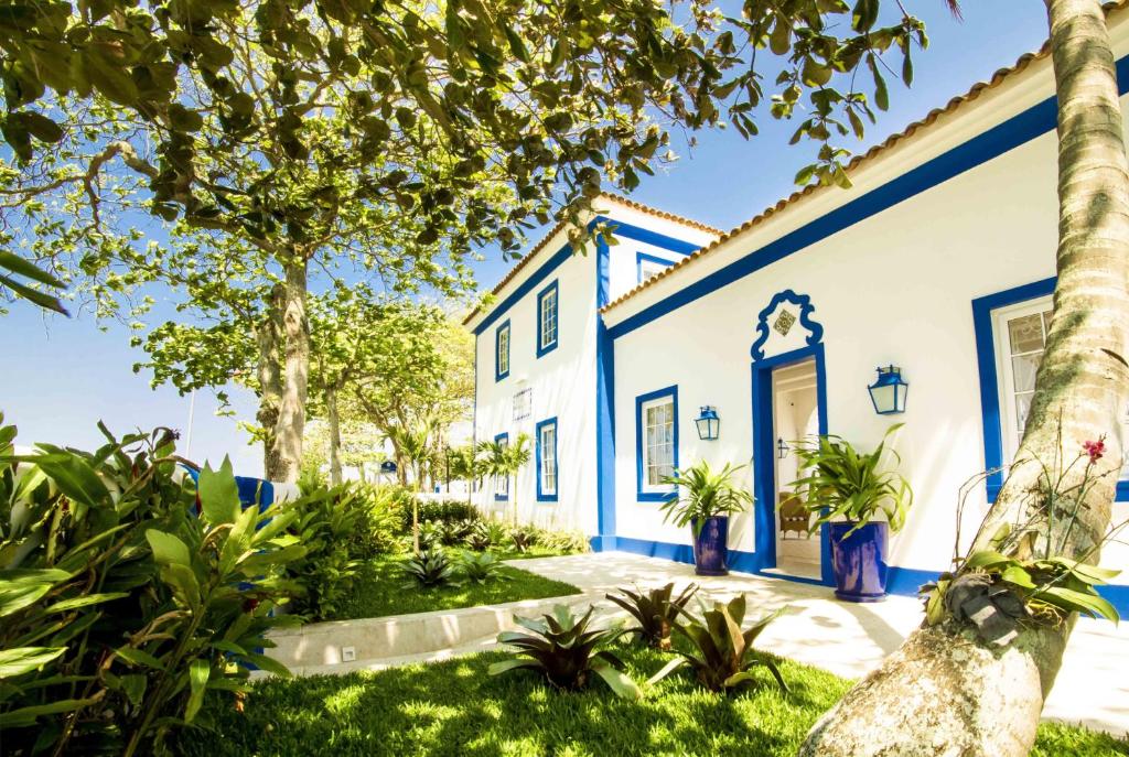 a blue and white house with palm trees at Hotel Solar do Arco in Cabo Frio