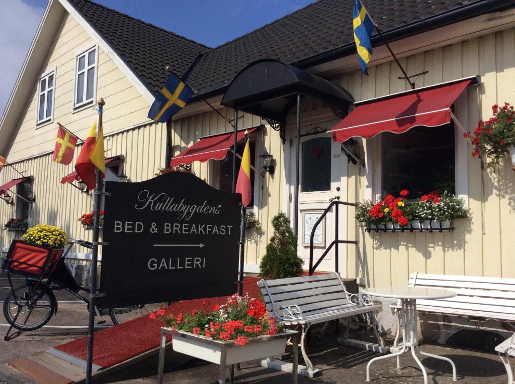 un cartel frente a un restaurante con banderas y flores en Kullabygdens Bed & Breakfast, en Jonstorp