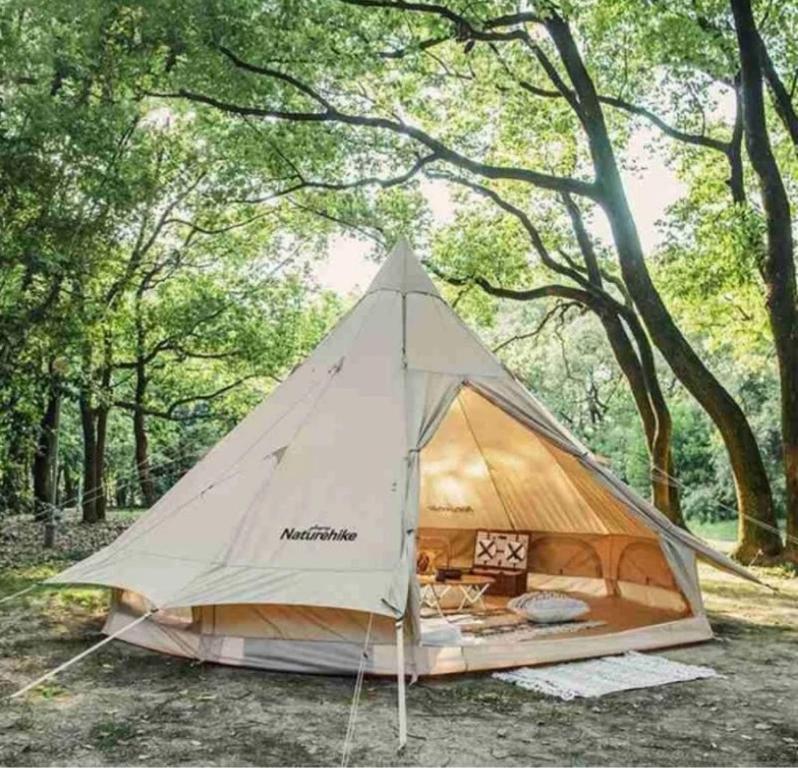 a tent in a field with trees in the background at Lembah Bromo in Gubukklakah