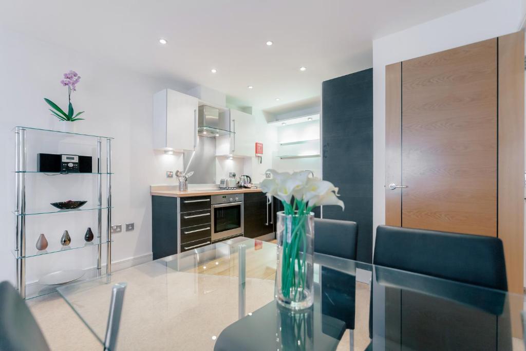 a vase of flowers on a glass table in a kitchen at Roomspace Serviced Apartments - Abbot's Yard in Guildford