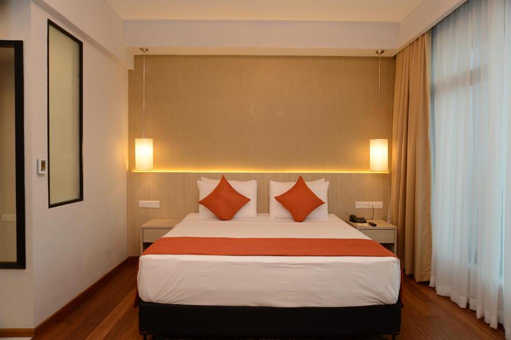 a bedroom with a large bed with orange pillows at Anarva Hotel & Spa in Mount Lavinia