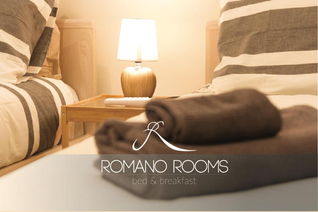 a bedroom with two beds and a table with a lamp at Romano Rooms in Catania