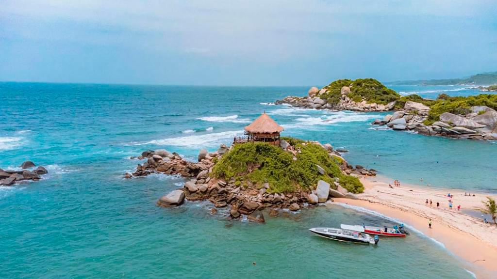 a small island in the ocean with two boats on it at HOSTAL MIRADOR dentro del parque tayrona in El Zaino