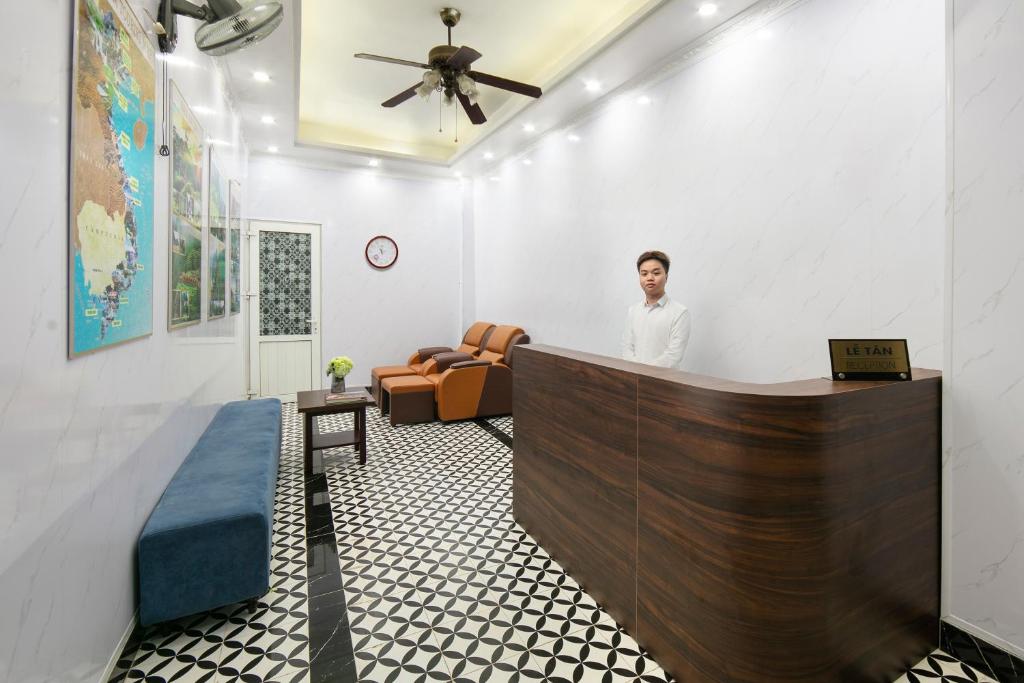 a man standing at a reception desk in a room at The La Renta Hotel & Spa in Hanoi