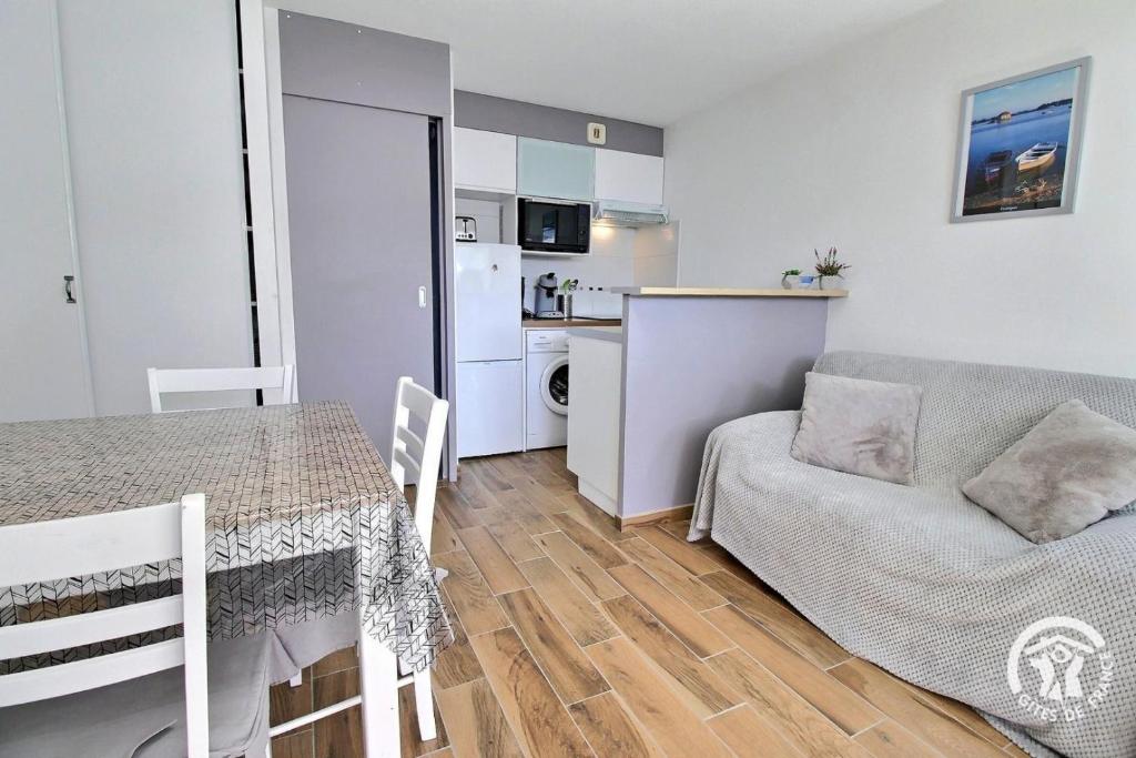 un salon avec une table et un canapé et une cuisine dans l'établissement La garenne, à Carnac