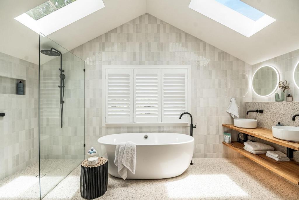 a bathroom with a large tub and a shower at Frangipani Cottage - Belle Escapes Byron Bay | Winter Escape Deal | Stay Longer & Save | 1 June – 31 August in Byron Bay