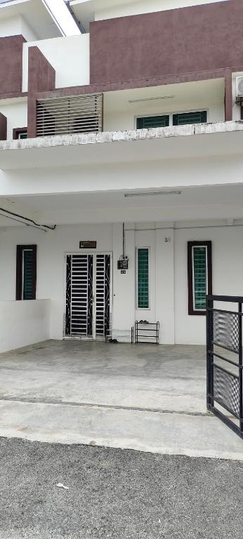 a white building with green windows and a gate at Inaz Homestay Alor Setar in Kampong Masjid