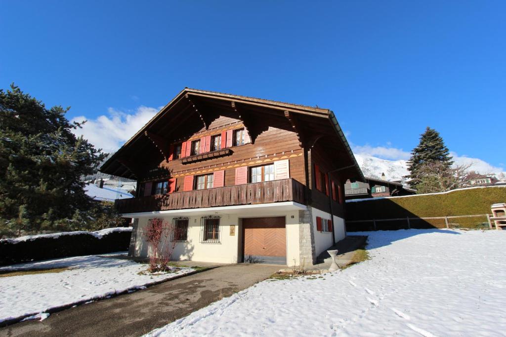 ein Holzhaus mit einer Garage im Schnee in der Unterkunft Chalet Les Arolles in Chateau-d'Oex