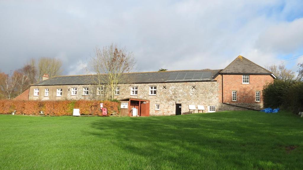 a large brick building with a green field in front of it at Exmouth Country Lodge and Cottage in Exmouth