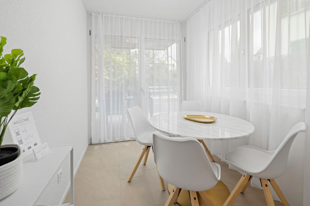 a white dining room with a white table and chairs at STAYY Flagship Limmattal - contactless check-in in Schlieren