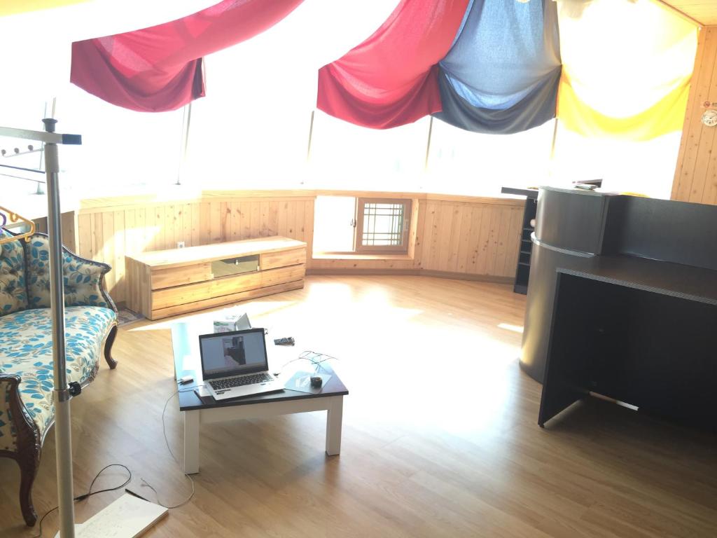 sala de estar con TV y mesa con ordenador portátil en Shinyang Beach Pension, en Seogwipo