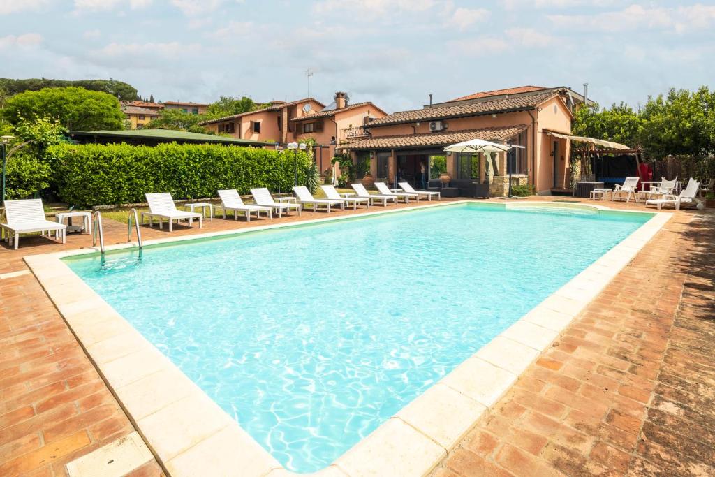 a swimming pool with chairs and a house at Villa delle Rose by VacaVilla in Magione