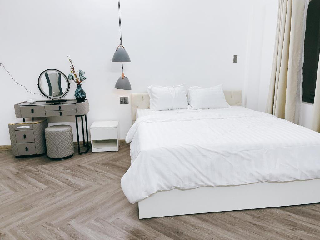 - une chambre blanche avec un lit blanc et un miroir dans l'établissement Kinh Do Homestay, à Hương Trà