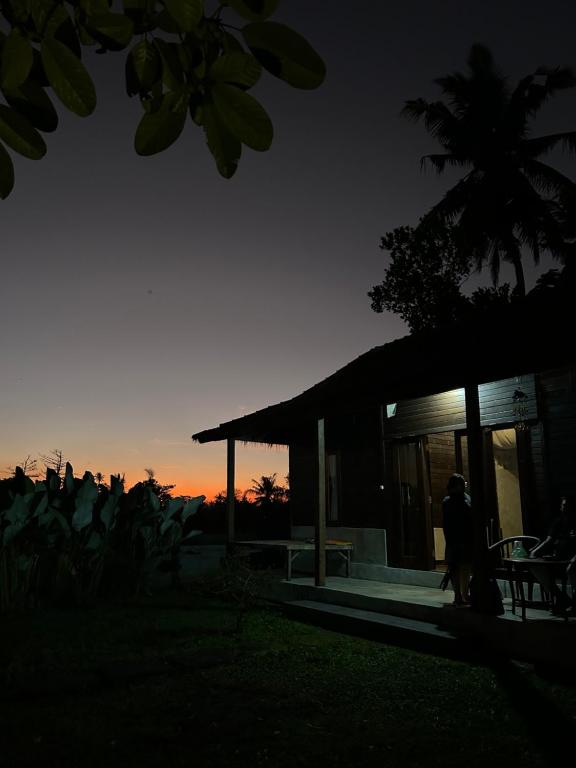 a group of people standing outside a building at sunset at Pondok Genitri in Bringkit