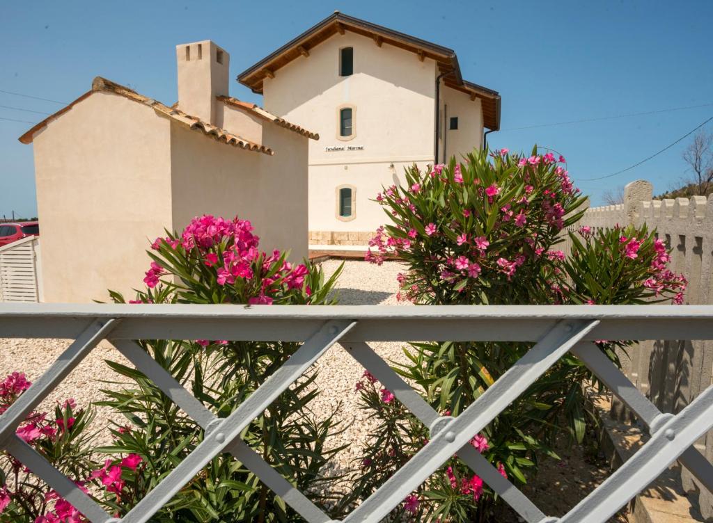 a house with pink flowers in front of a fence at B&B Fermata 106 da Carolina in Siculiana Marina