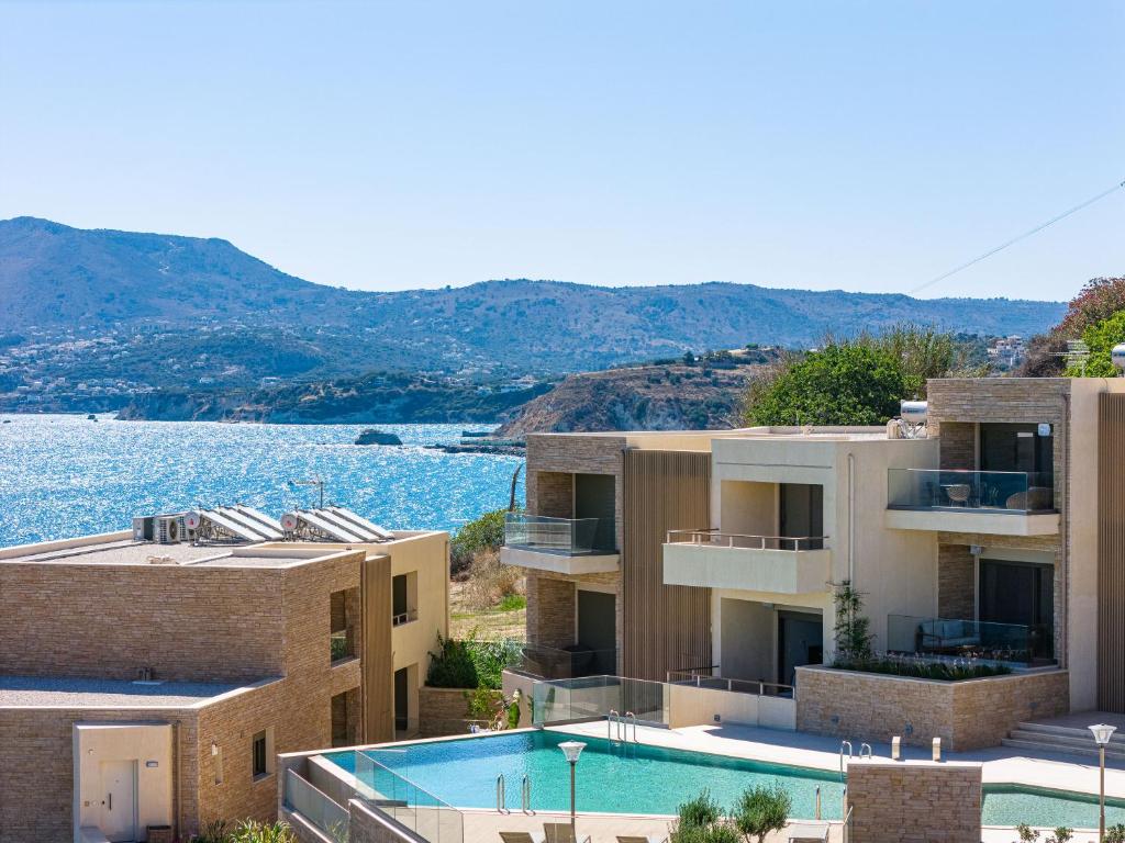 a building with a swimming pool next to a body of water at Panorama Seaview Village at Kalyves in Kalyves