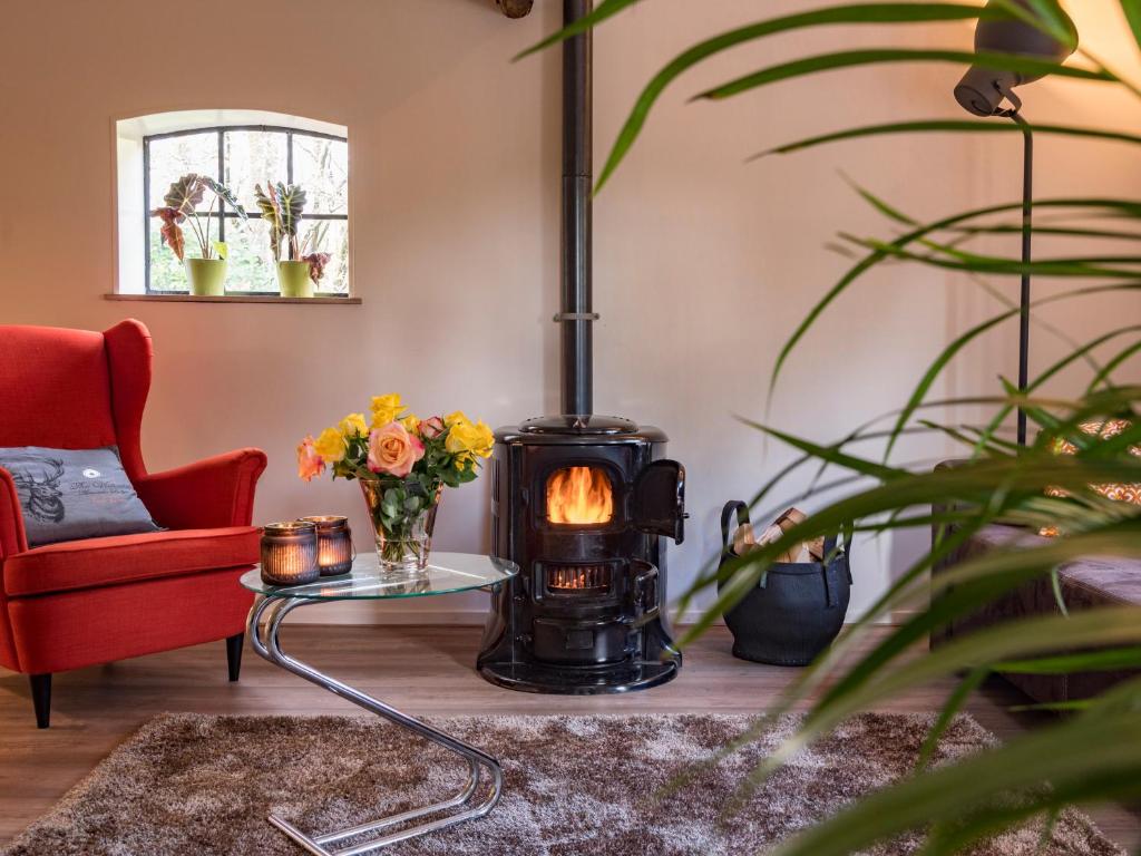 een woonkamer met een houtkachel en een rode stoel bij Bed En Comfort in Vaassen