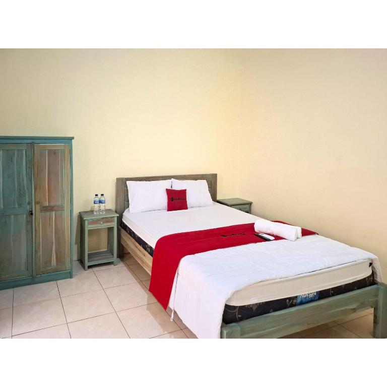 a bedroom with two beds with white sheets and a red blanket at RedDoorz near Alun Alun Jepara in Kesembu