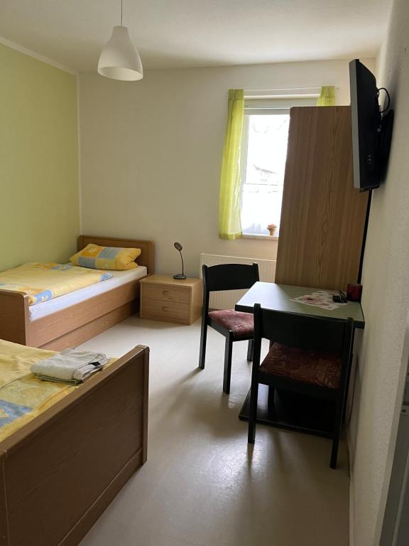 a room with two beds and a table and a desk at Pension Gasthaus Schützenhaus in Waldenburg