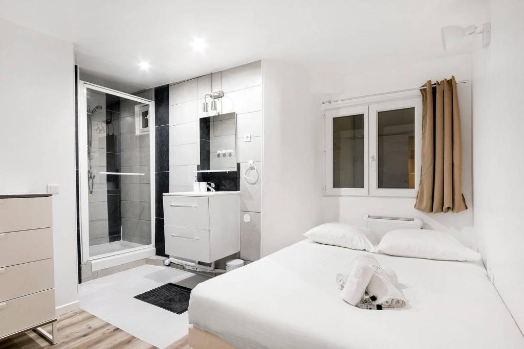 - une chambre blanche avec un lit et une douche dans l'établissement GuestReady - Central Apt in Paris, à Paris