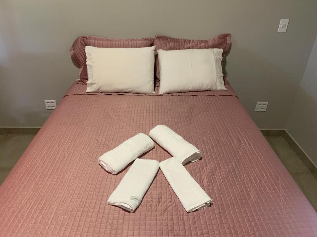 a bed with two pillows and a x on it at Chácara Primavera in Capão Bonito