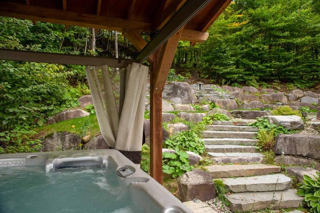 a hot tub under a gazebo next to some stairs at Héritage Nature Scandinavian Chalet Spa & View in Sainte-Adèle