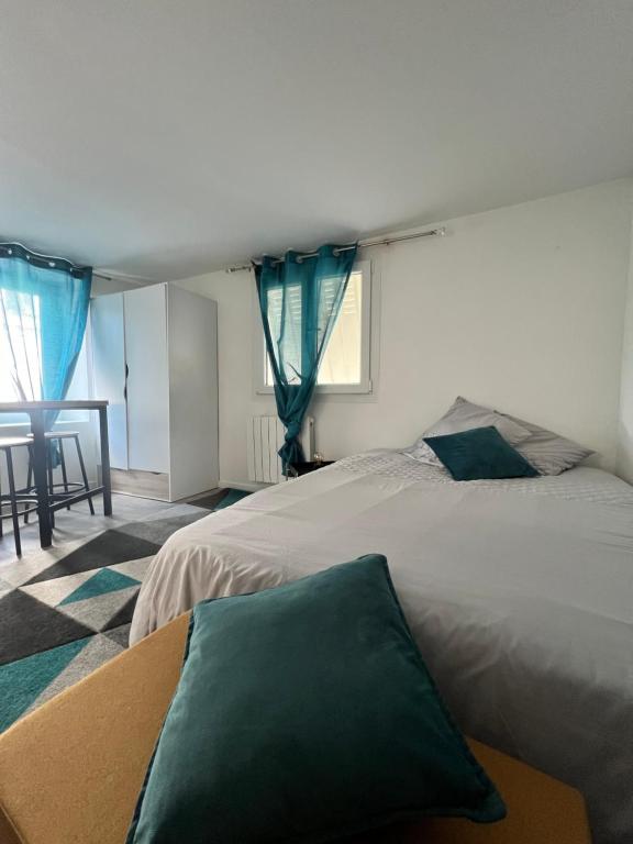 a bedroom with two beds with blue curtains and a table at Studio Cozy proche aéroport CDG in Claye-Souilly