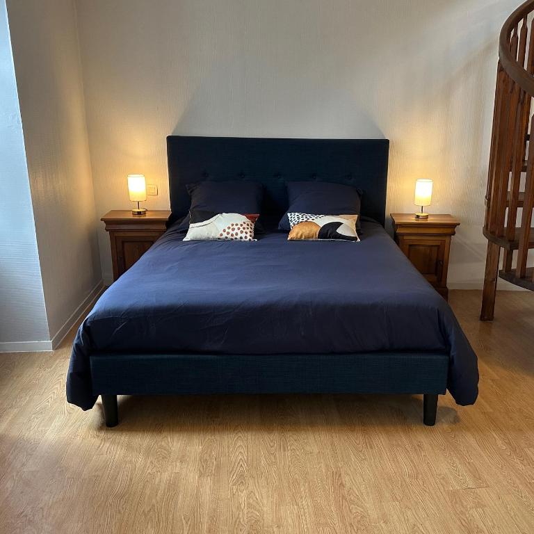 - un lit bleu avec des oreillers dans la chambre dans l'établissement Gîte au cœur de la ville ancienne, à Terrasson