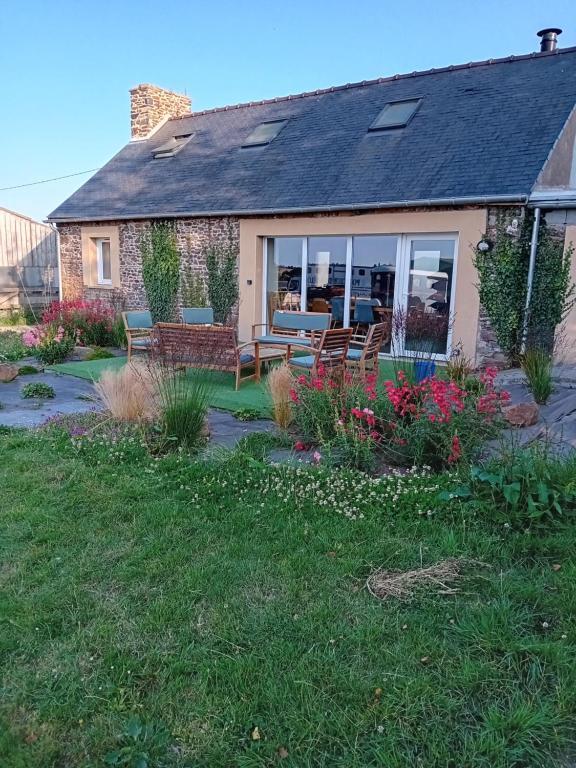 une maison avec une terrasse agrémentée de bancs et de fleurs dans l'établissement Équi'séjour, à Pordic