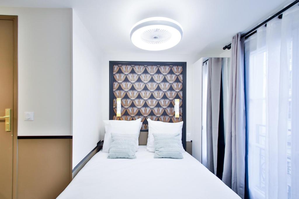 - une chambre avec un grand lit blanc et des oreillers blancs dans l'établissement WS Opéra - Duphot, à Paris