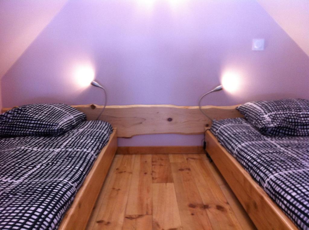 two beds in a room with purple walls and wooden floors at Chez Pépé in Génos