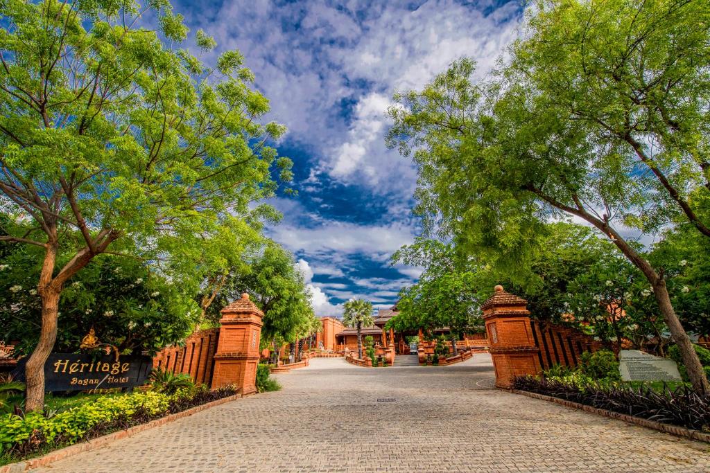 a brick driveway with trees and a fence at Heritage Bagan Hotel in Bagan
