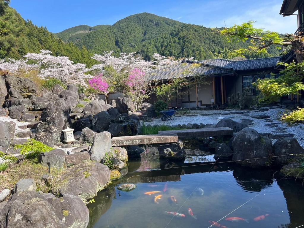 a garden with a pond and a bridge and a house at すいこうえんさくら in Fujinomiya