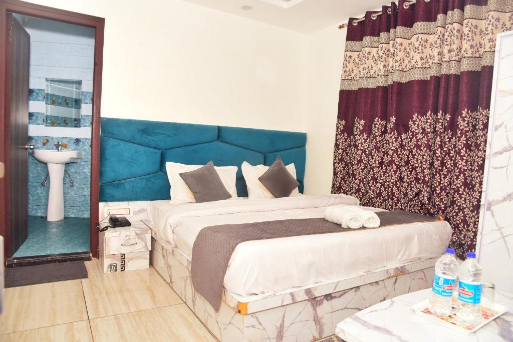 a bedroom with a large bed with a blue headboard at Hotel Elegance, Katra in Katra