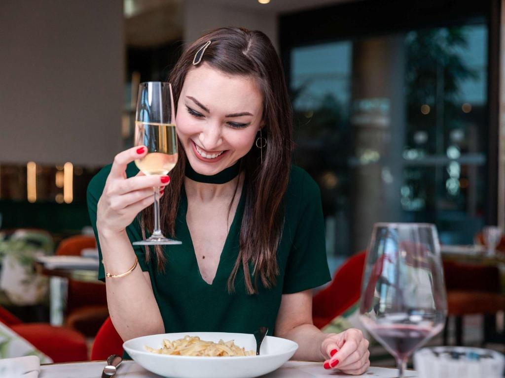 a woman sitting at a table with a glass of wine at Sofitel Luxembourg Europe in Luxembourg