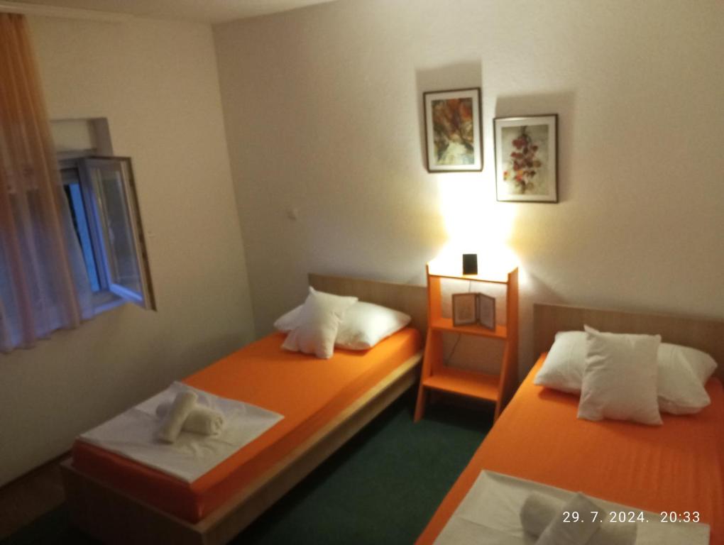 two twin beds in a room with a lamp at Vacanza apartment in Mostar