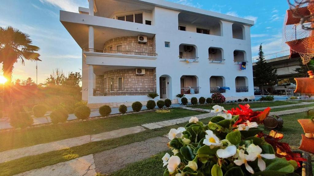 un grand bâtiment blanc avec des fleurs devant lui dans l'établissement Sunny apartments, à Ulcinj