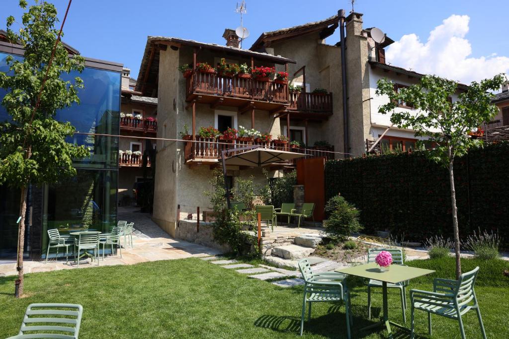 a garden with chairs and tables and a building at Maison Bondaz & SPA priv&eacute; in Aosta