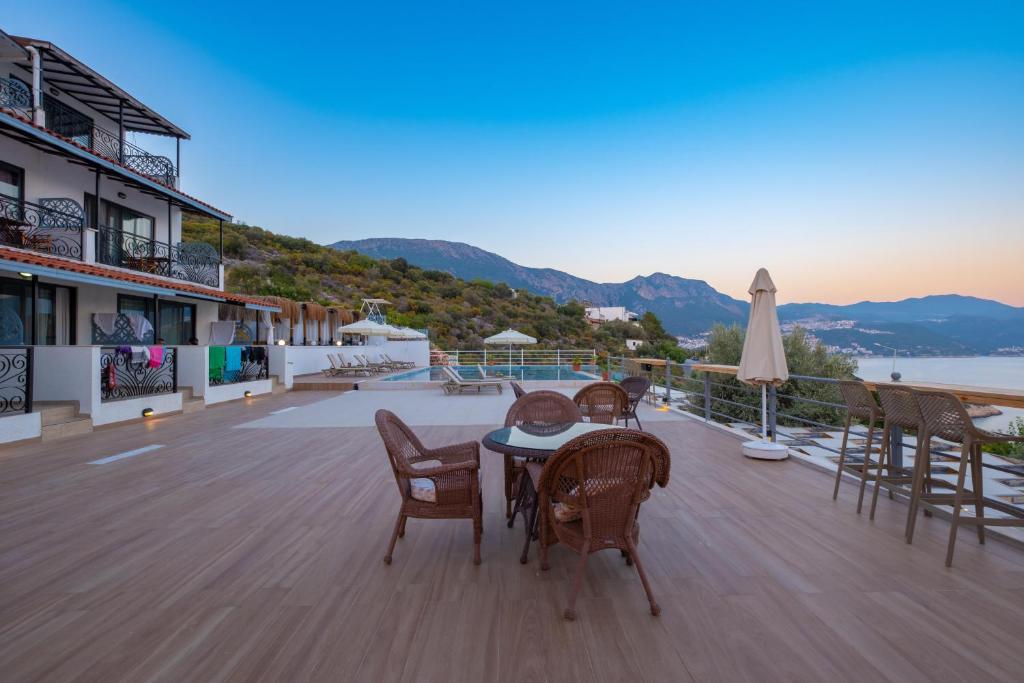 a table and chairs on a deck with a view of the ocean at Hamarat Otel in Kaş