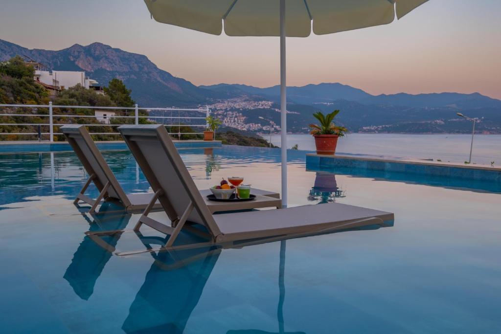 a lounge chair with an umbrella next to a swimming pool at Hamarat Otel in Kaş