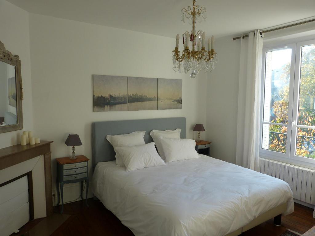 Un dormitorio con una cama con sábanas blancas y una lámpara de araña. en Villabona, en Orsay