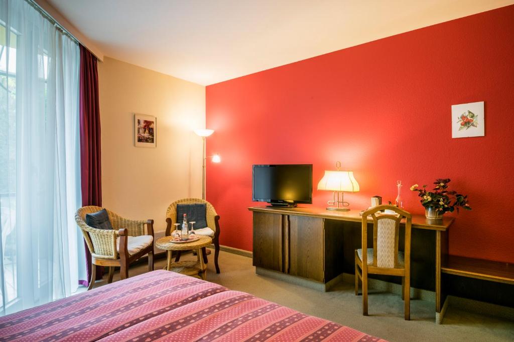 a hotel room with a bed and a flat screen tv at Hotel Restaurant Le Cigalon in Waldbillig