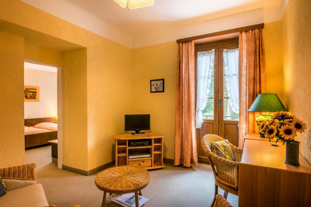 a living room with a television and a desk with a computer at Hotel Restaurant Le Cigalon in Waldbillig