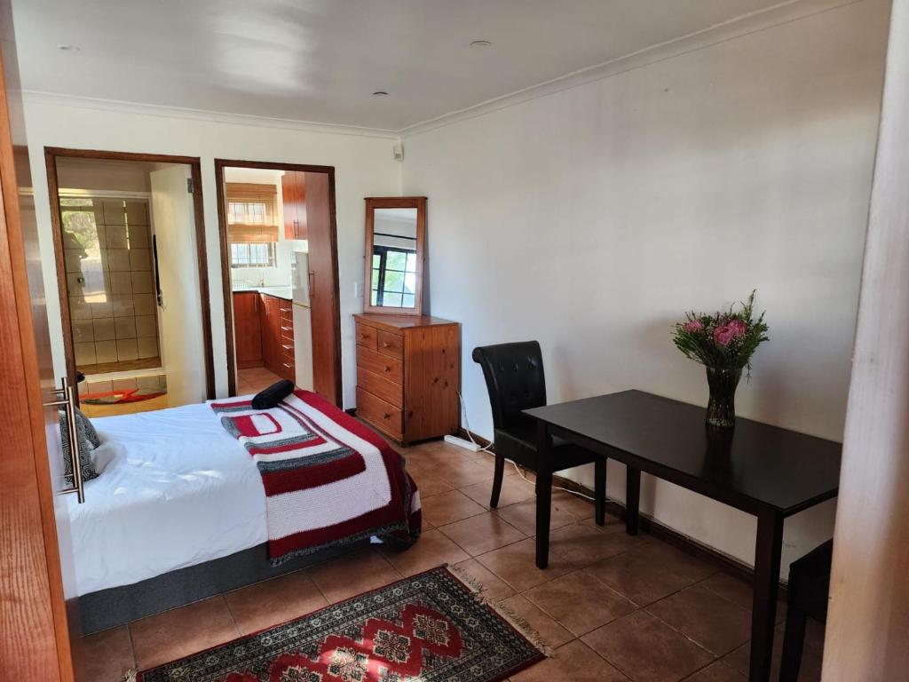 een slaapkamer met een bed, een bureau en een tafel bij Cape Cottage in Kaapstad