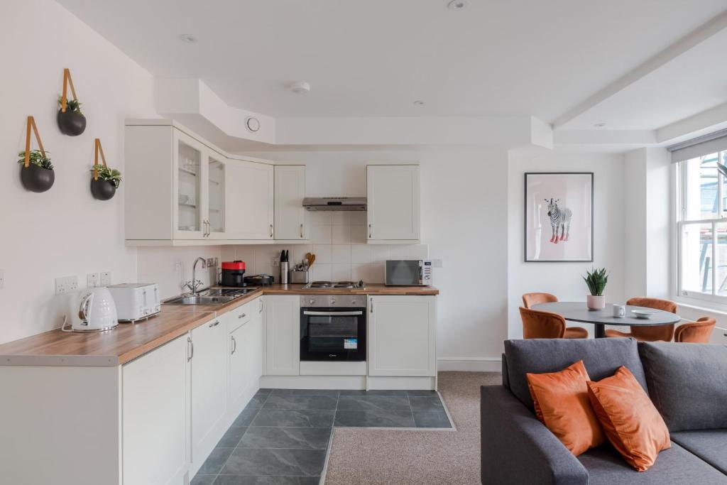 a kitchen and living room with white cabinets and a couch at The Vanity Affair - Fitzrovia - By Frankie Says in London