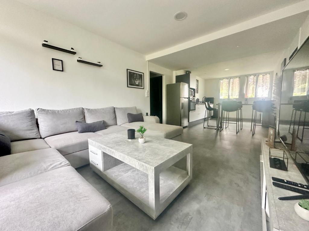 a living room with a white couch and a table at Le Monochrome, spacieux et adapté aux familles in Limoges